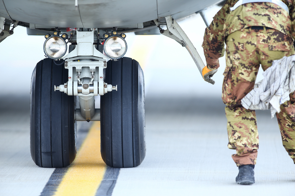 an army mechanic inspects military aircraft landing gear