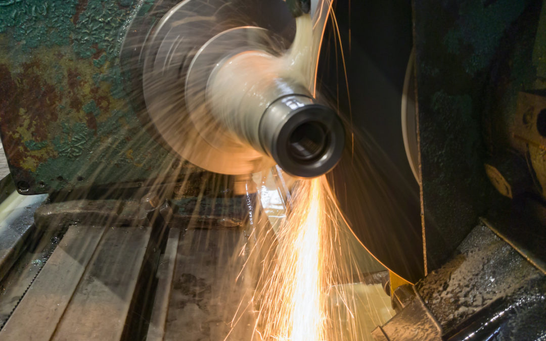 Metal billet on a circular grinding machine, flying sparks from under a circle with water cooling.