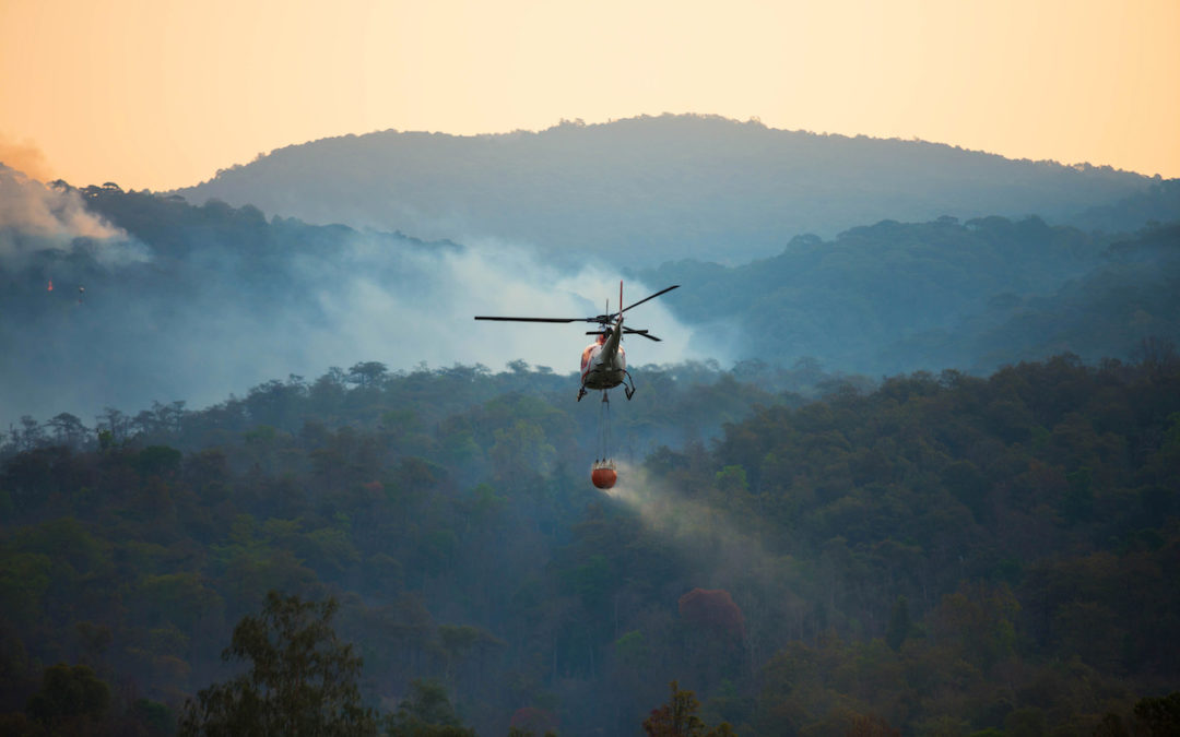 A firefighting helicopter gathers water to extinguish a wildfire in the mountains.