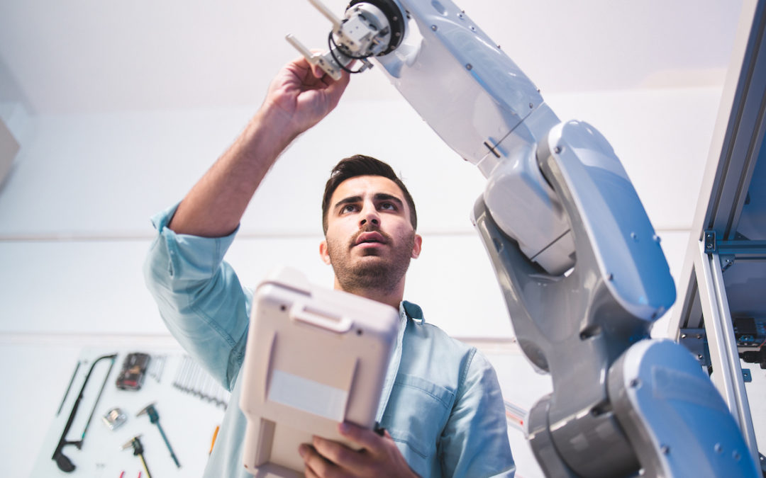 An engineer adjusts a robotic arm in a testing facility.