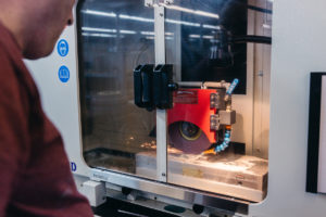 A machine operator monitors precision surface grinding.