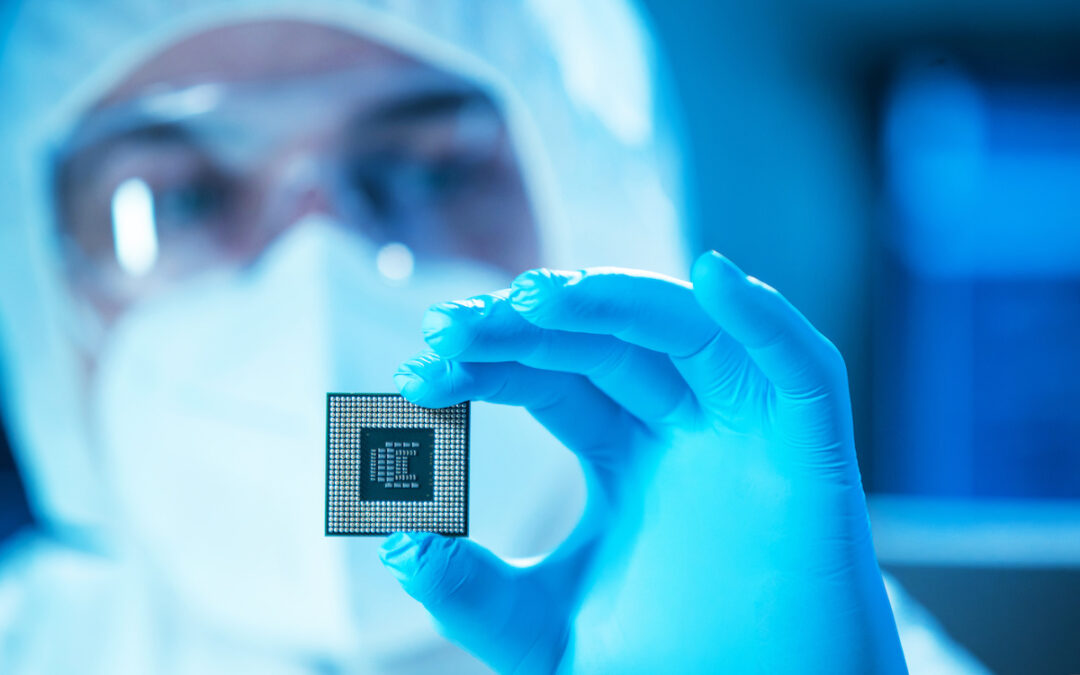 Professional scientist works in a modern scientific laboratory for the research and development of microelectronics and processors. Microprocessor manufacturing worker in blue gloves and mask uses computer technology and equipment.